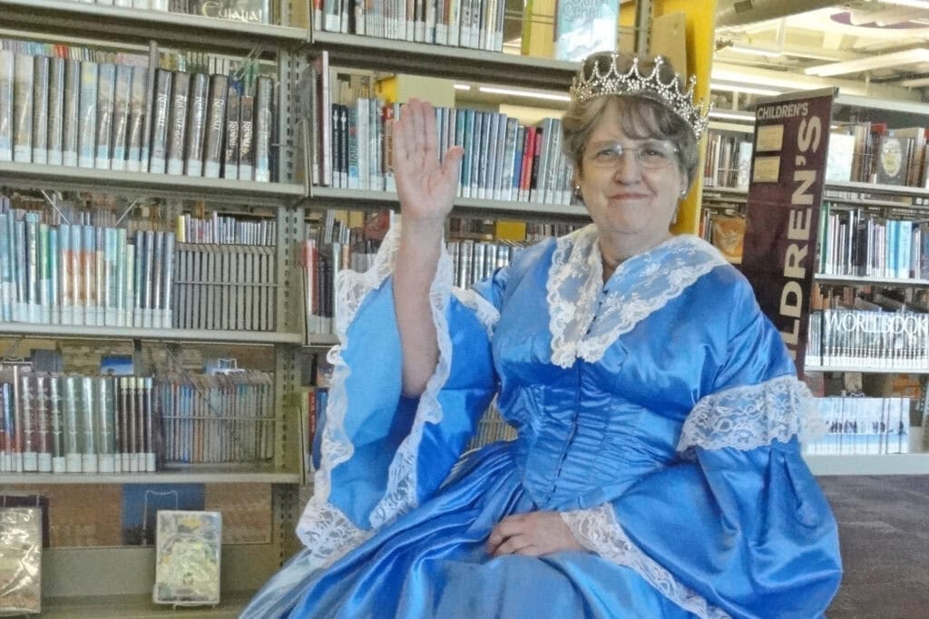 woman (vicky hays) in fancy dress waving at the camera